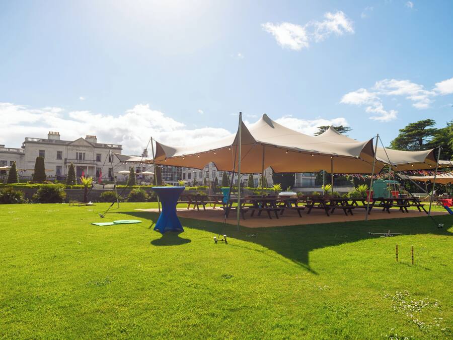 A grassy outdoor area with picnic tables and a blue table.