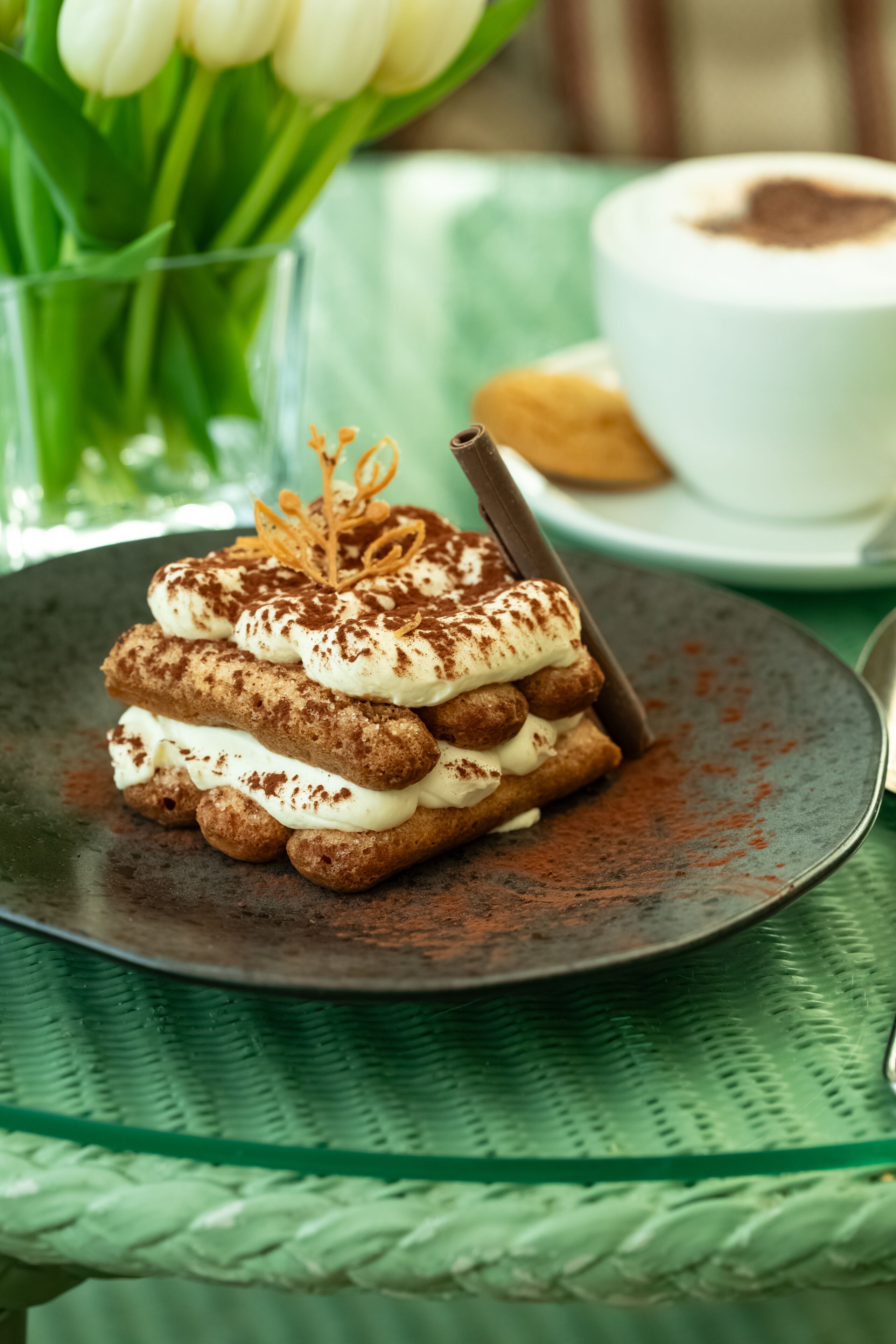 A dessert on a plate with a chocolate stick, surrounded by a green tablecloth.