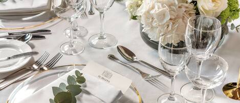 A table set with white plates, clear glassware, and a floral centerpiece.