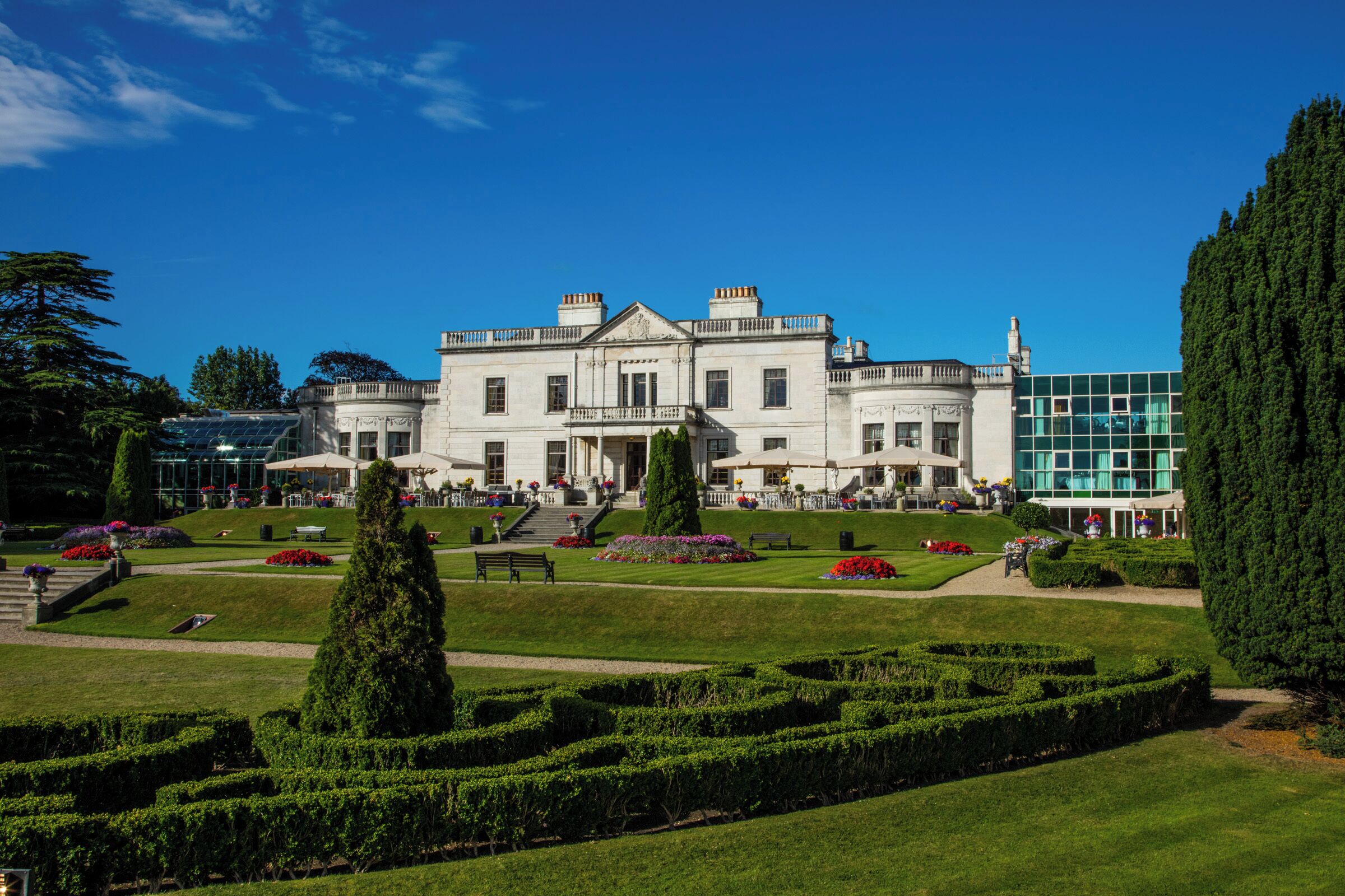 Een groot, historisch gebouw met een formele tuin, inclusief een doolhof en verzorgde gazons.