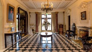Un suelo a cuadros, un candelabro, una chimenea y un letrero que indica sala de estar.