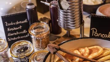 A breakfast buffet with pancakes, syrup dispensers, and various condiments.