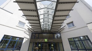 A modern building with a glass facade, a sign reading "ibis Berlin Treptow," and two large potted plants at the entrance. - ibis Styles Berlin Treptow (Berlin)