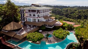 Un hôtel à plusieurs étages doté d’une piscine, d’un espace extérieur aménagé et offrant une vue sur la forêt environnante.