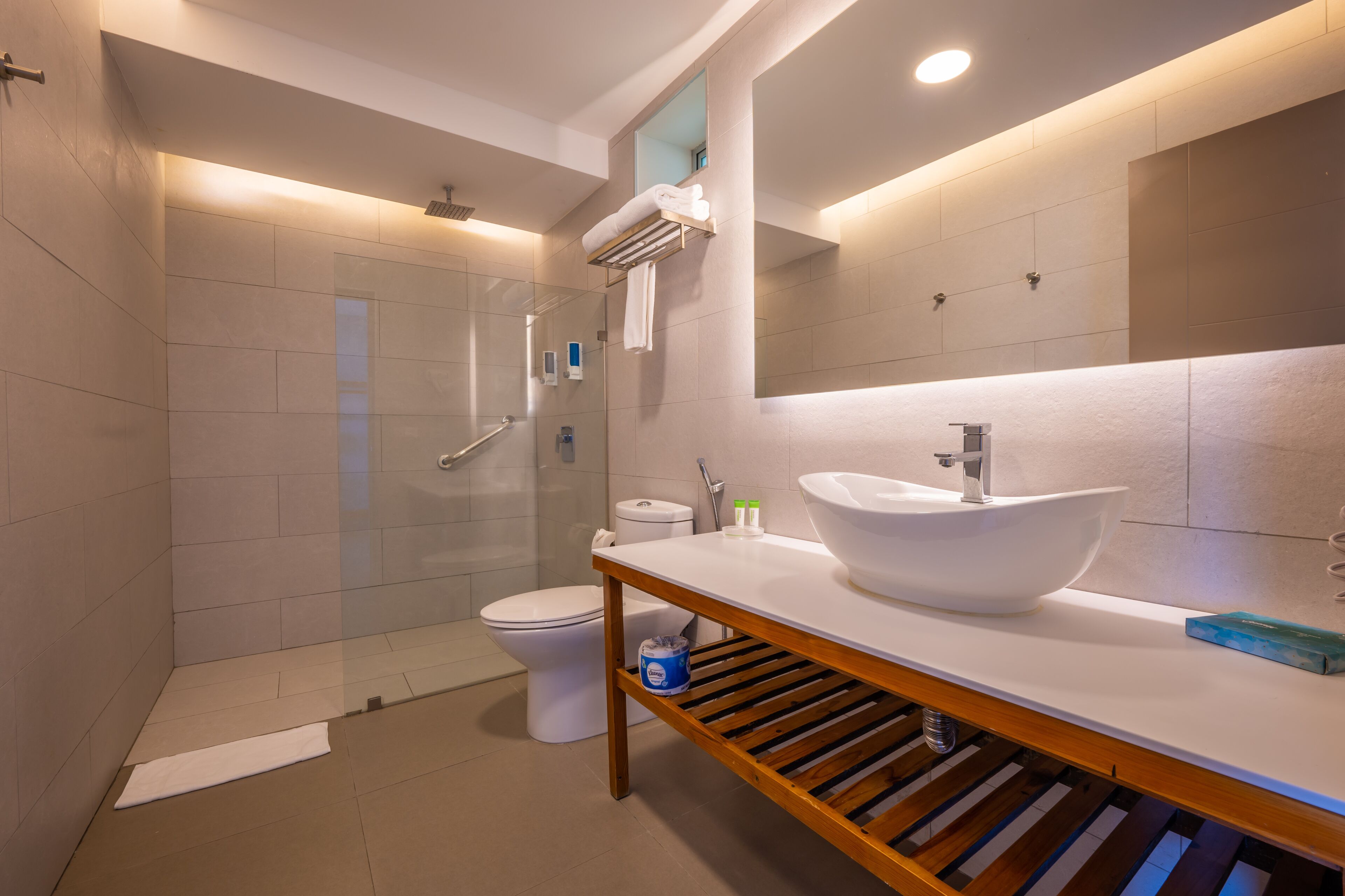 A modern bathroom with a glass-enclosed shower, a white sink, and a large mirror.
