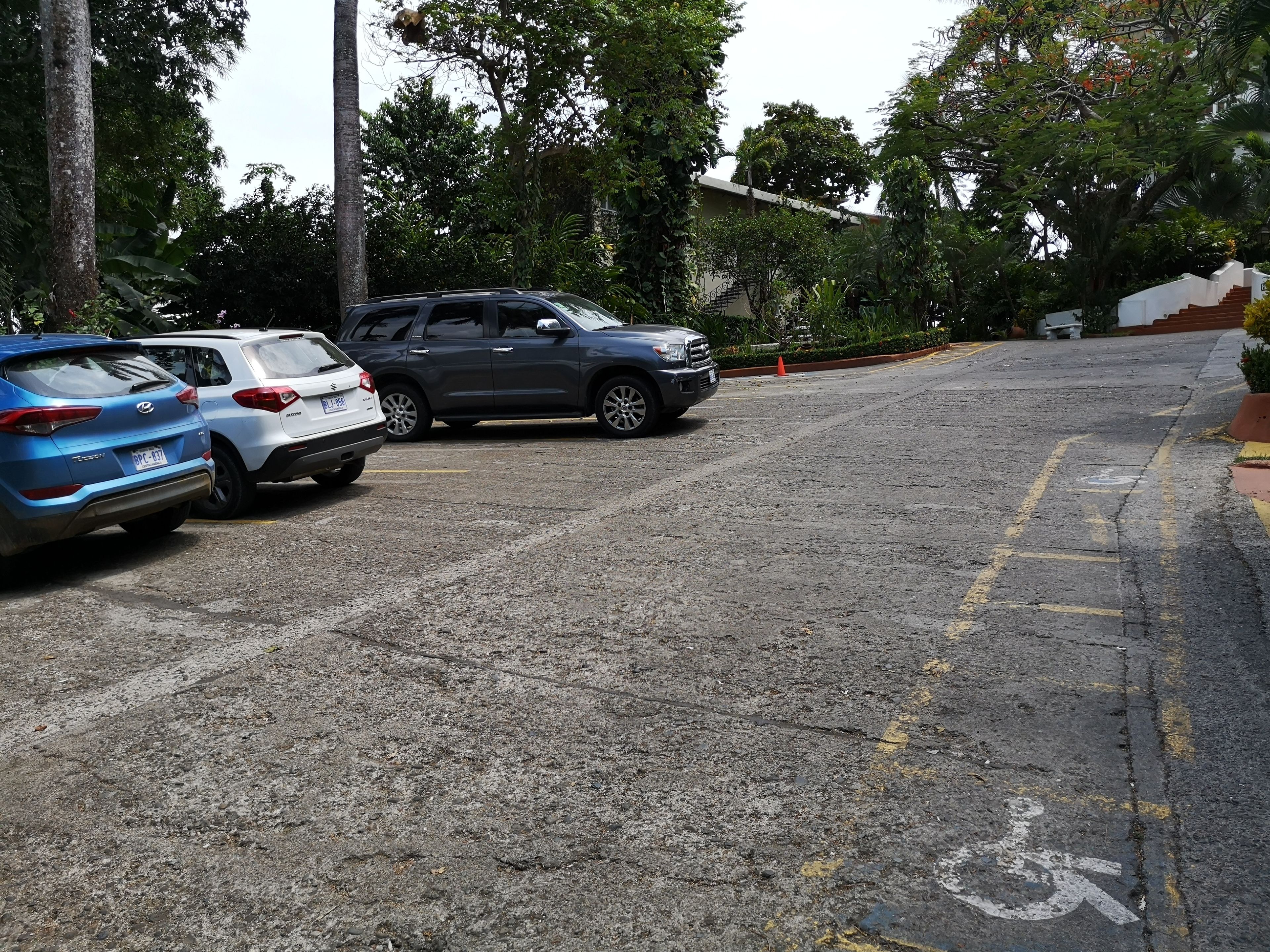 A parking area with three cars parked in a row.