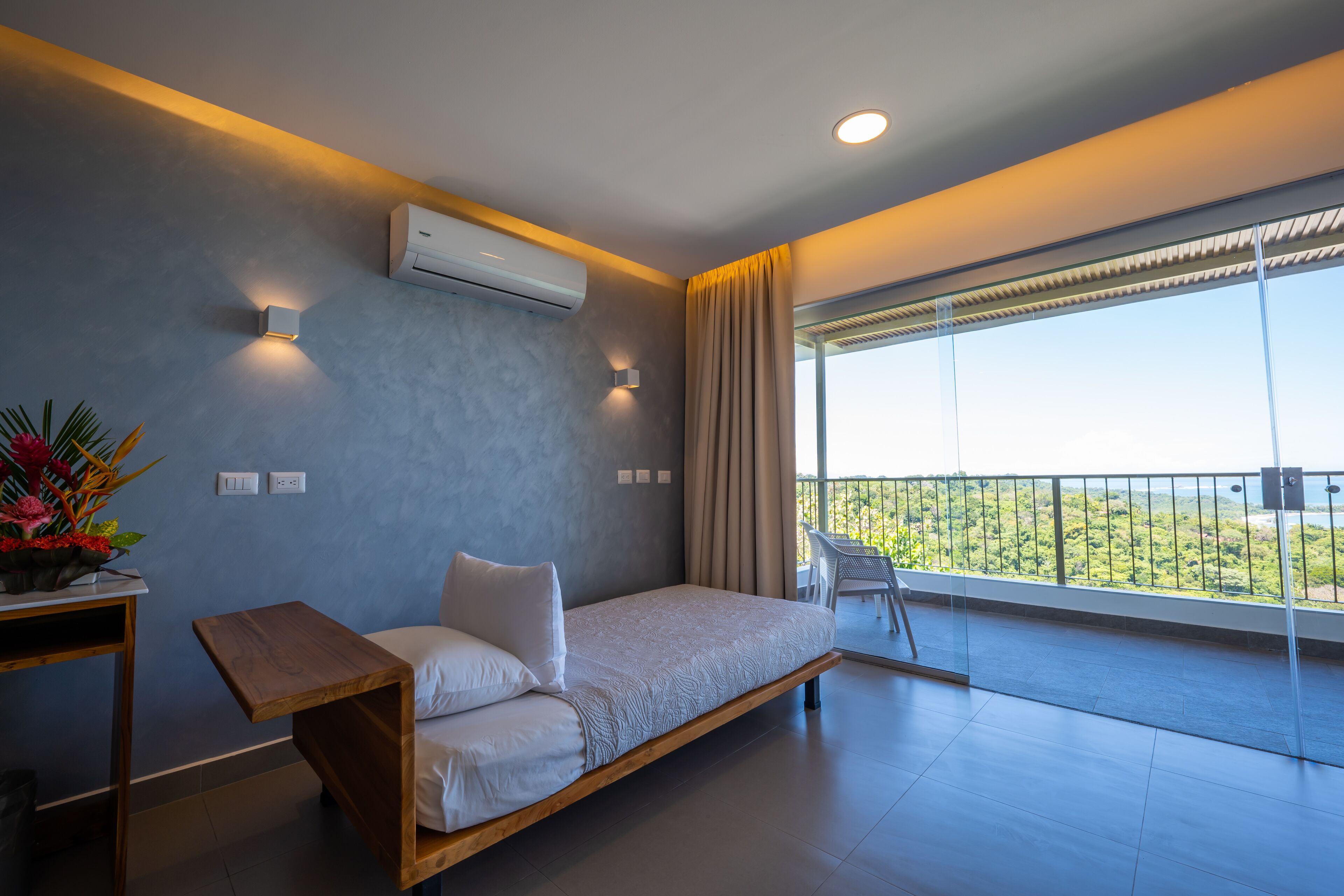 A modern bedroom with a bed, a small table, and a potted plant.