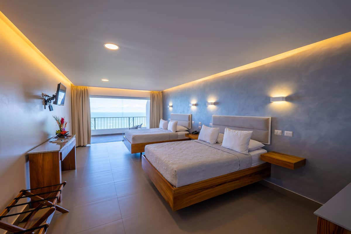 Une chambre d’hôtel moderne avec deux lits, un bureau et un balcon offrant une vue agréable.