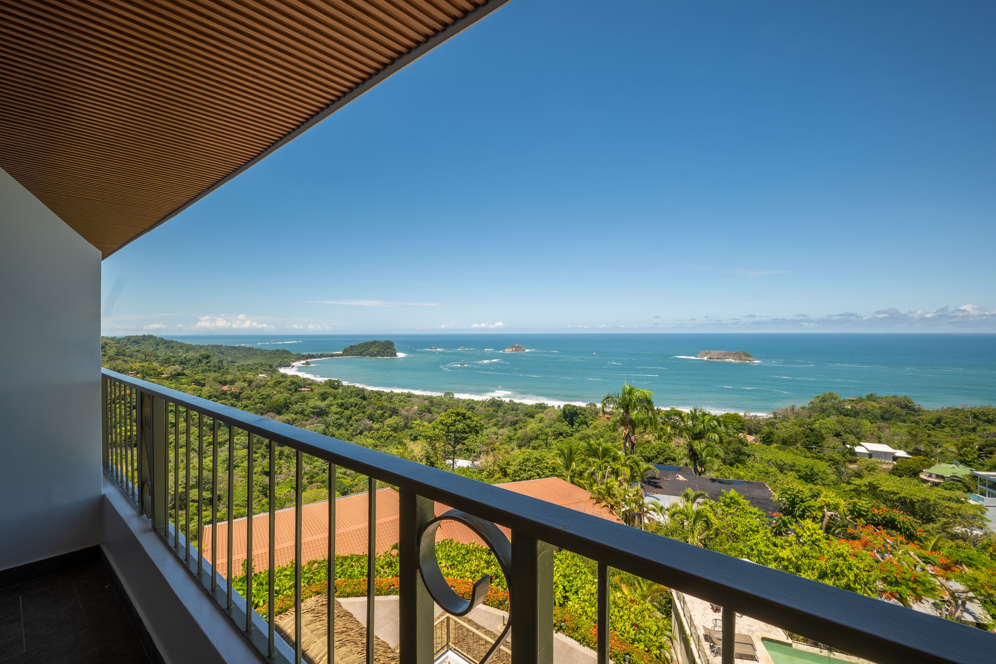 A balcony with a view of a coastal landscape, including the sea and greenery.