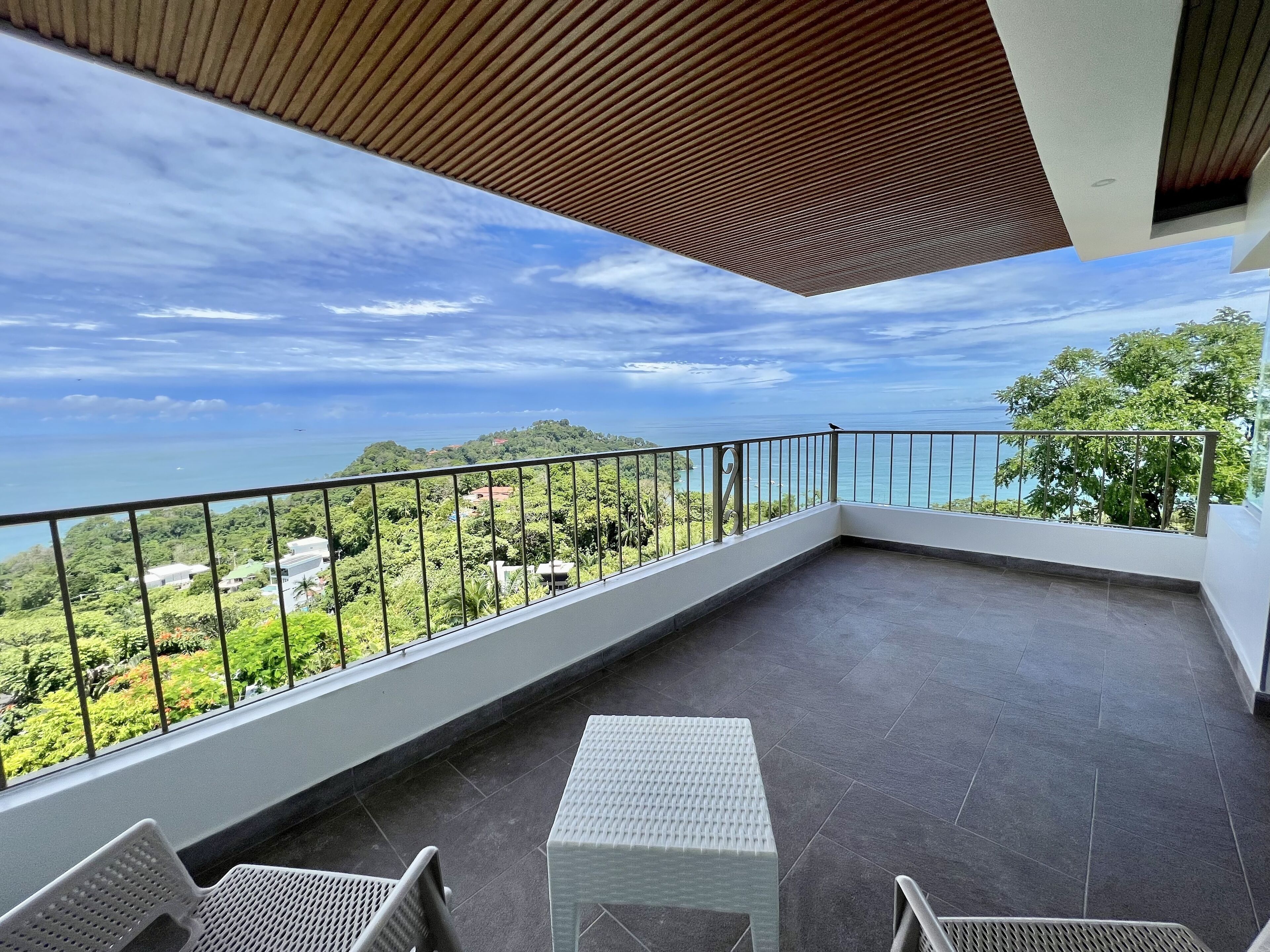 A balcony with a view of the sea and greenery.
