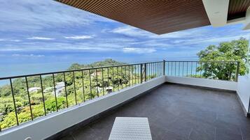 A balcony with a view of the sea and greenery.