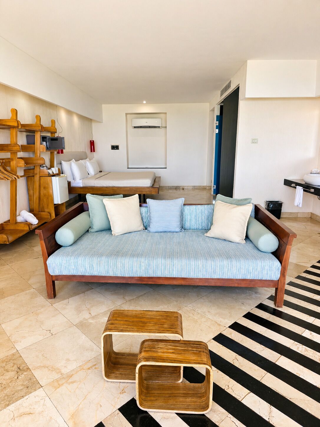 Een moderne hotelkamer met een bank, een bed, een televisie en een houten bijzettafeltje.