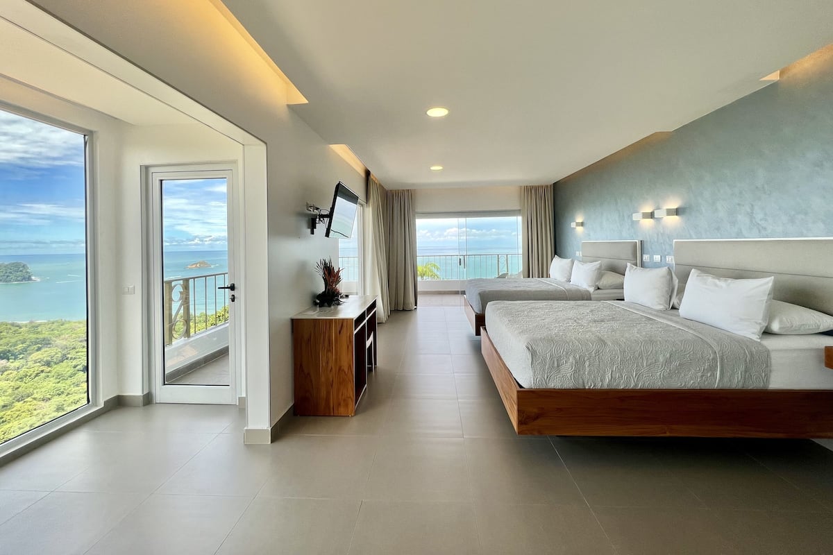 Une chambre d’hôtel moderne dotée d’un grand lit, d’un bureau et d’un balcon avec vue sur la mer.