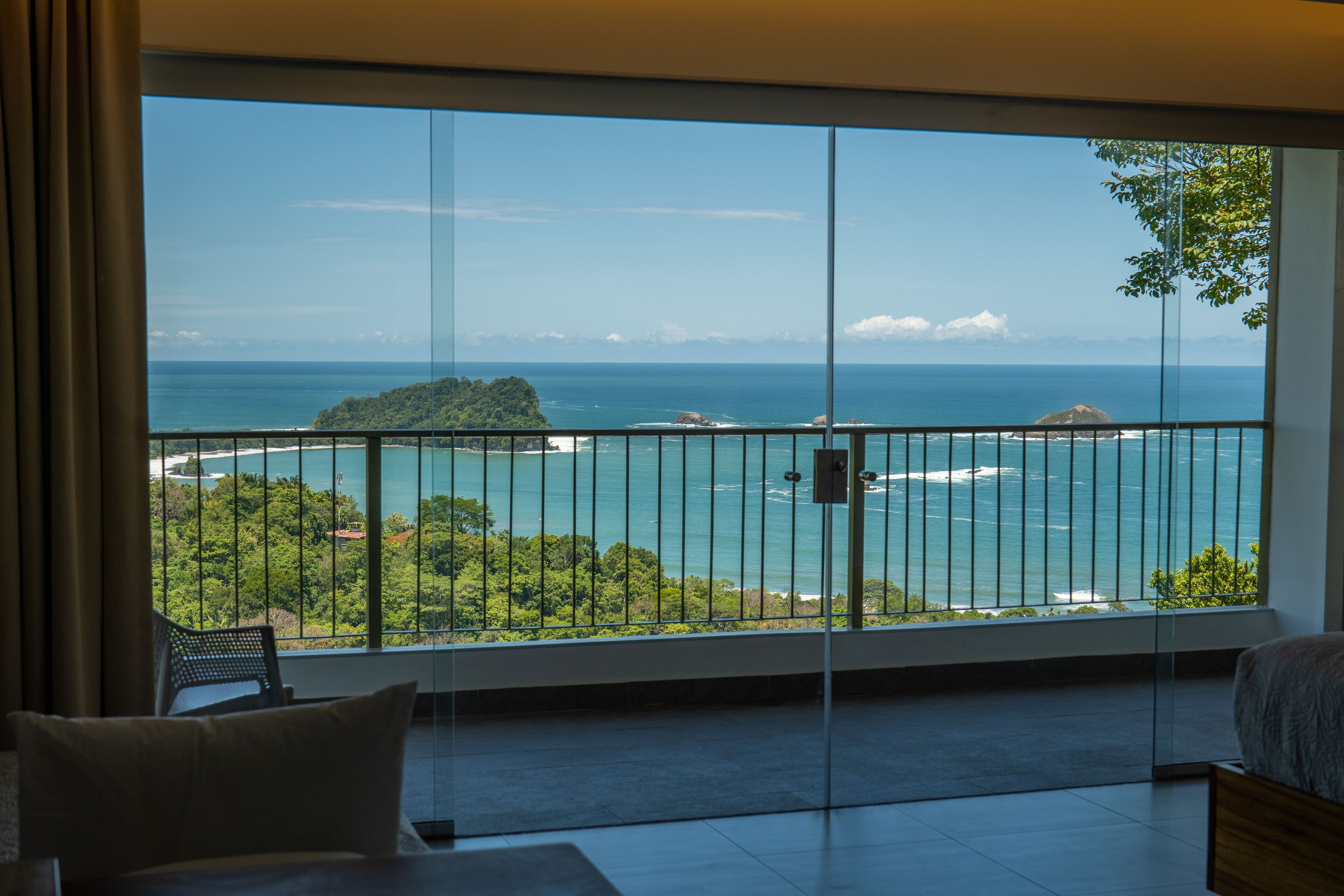 A balcony with a view of the sea and greenery.