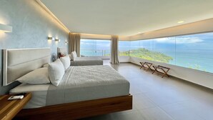 Ein modernes Schlafzimmer mit einem großen Bett, einem Nachttisch, einem Sessel und Meerblick.