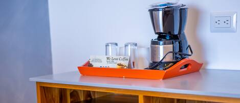 A compact kitchenette with a built-in mini-fridge and a coffee maker on a wooden countertop.