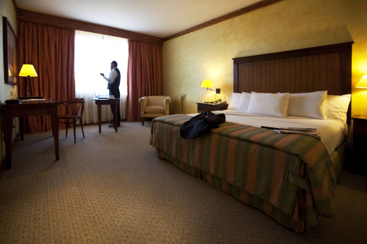 Una habitación de hotel con cama, escritorio, silla y lámpara.