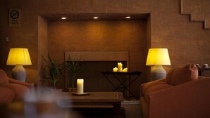Ein gemütliches Zimmer mit Backsteinwand, zwei Lampen, einem Kamin und einer Couch.
