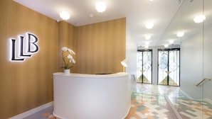 A reception area with a wooden wall and a white reception desk. - Le Lapin Blanc (Paris)