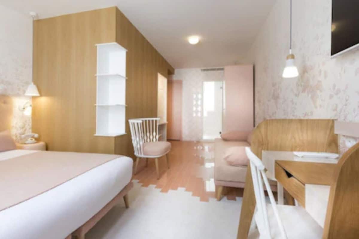 A modern bedroom with a bed, bedside table, chair, and a desk with a chair.