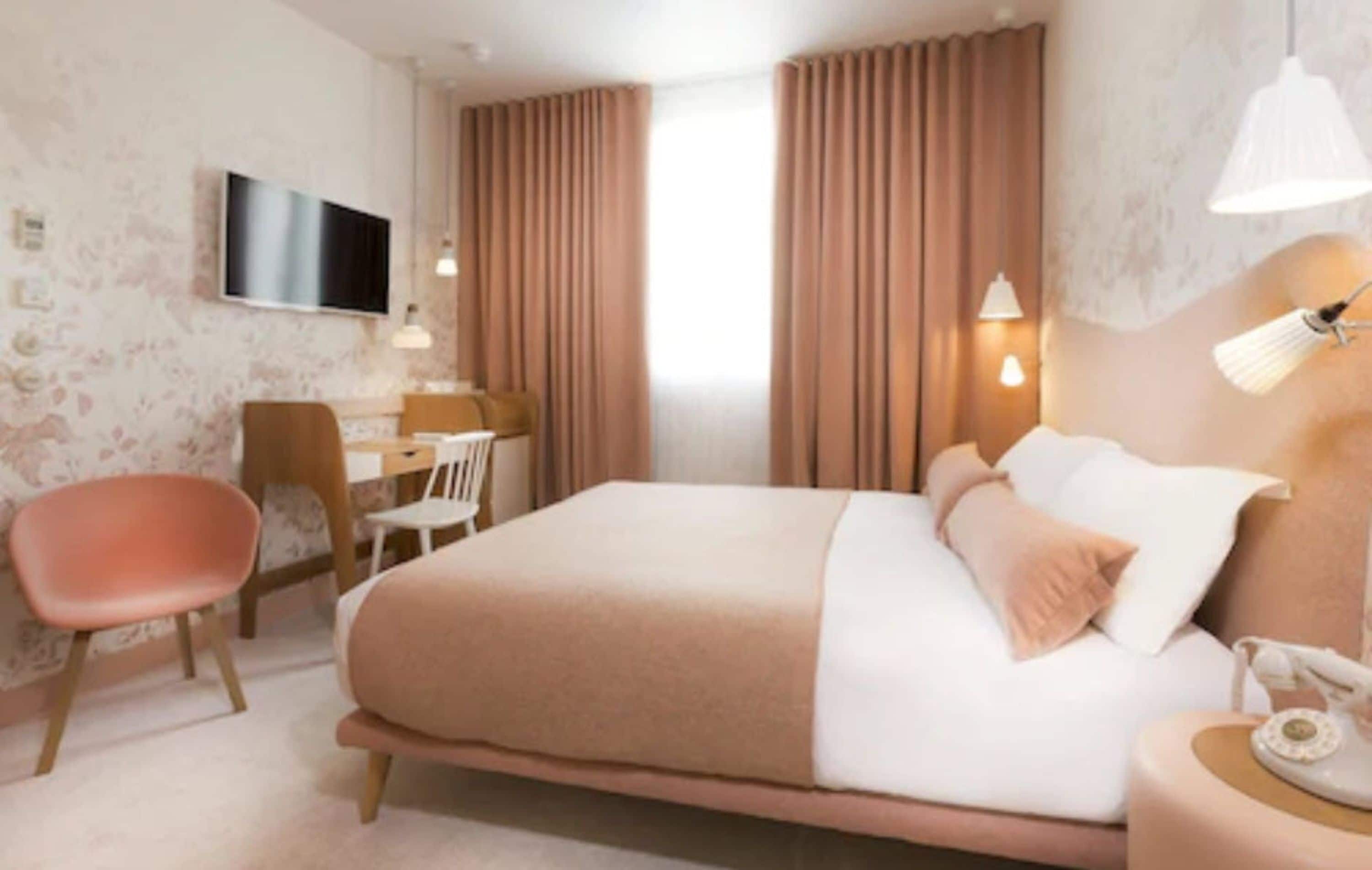 Une chambre d’hôtel moderne, dotée d’un grand lit, d’un bureau, d’une chaise et d’un téléviseur fixé au mur.