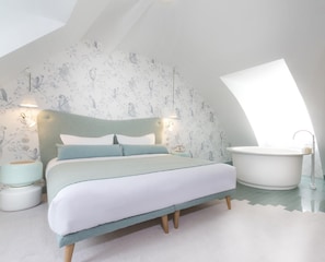 Quarto com cama, mesa de cabeceira, luminária, luz na parede e banheira.