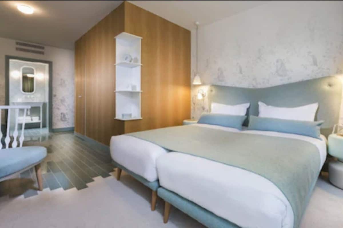 A modern bedroom with a large bed, bedside tables, a desk, and a chair.