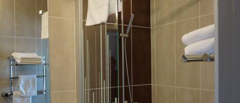 A modern bathroom with a glass-enclosed shower, a white sink, and a mirror.