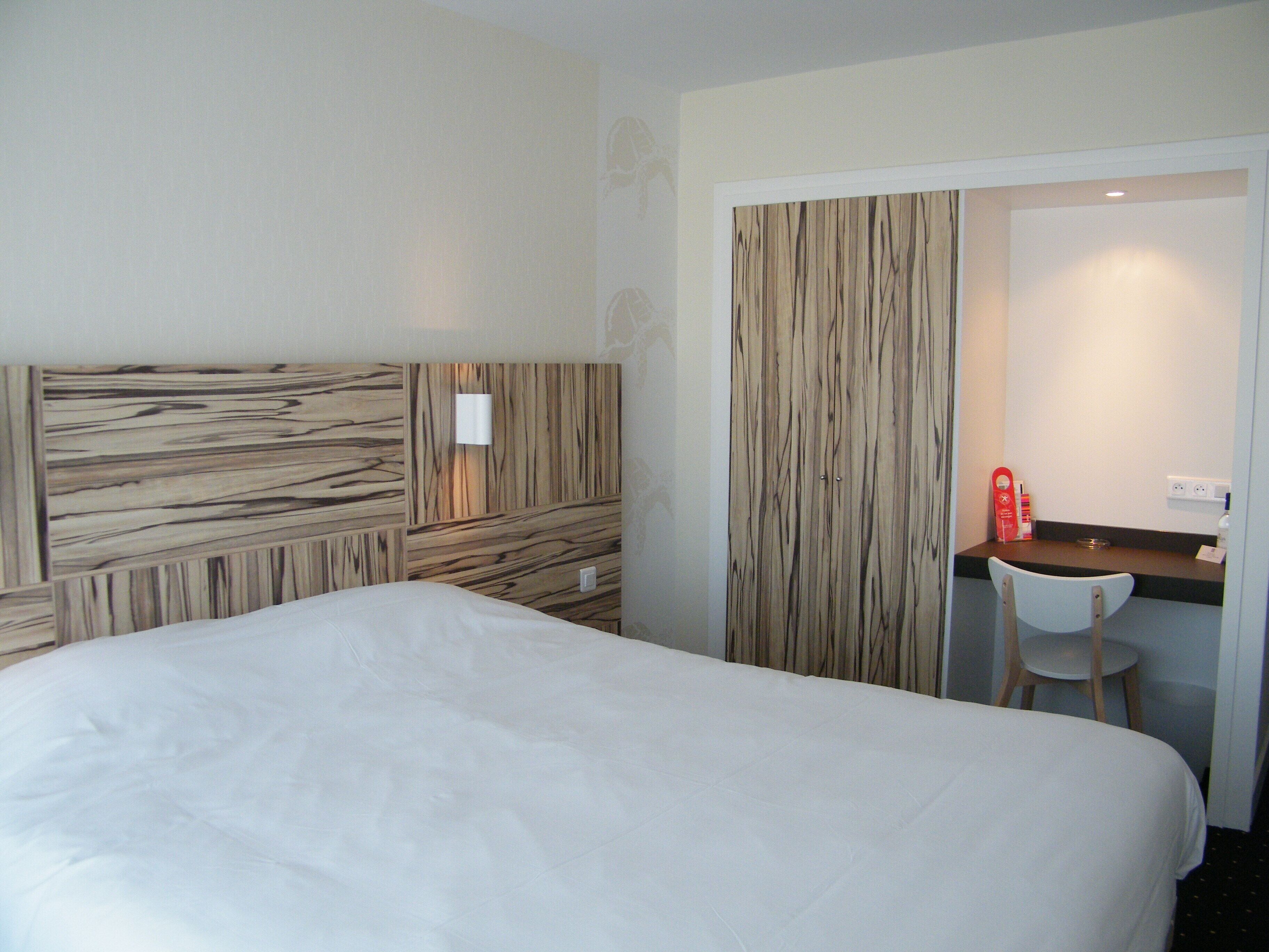 A hotel room with a large bed, a desk, and a chair.