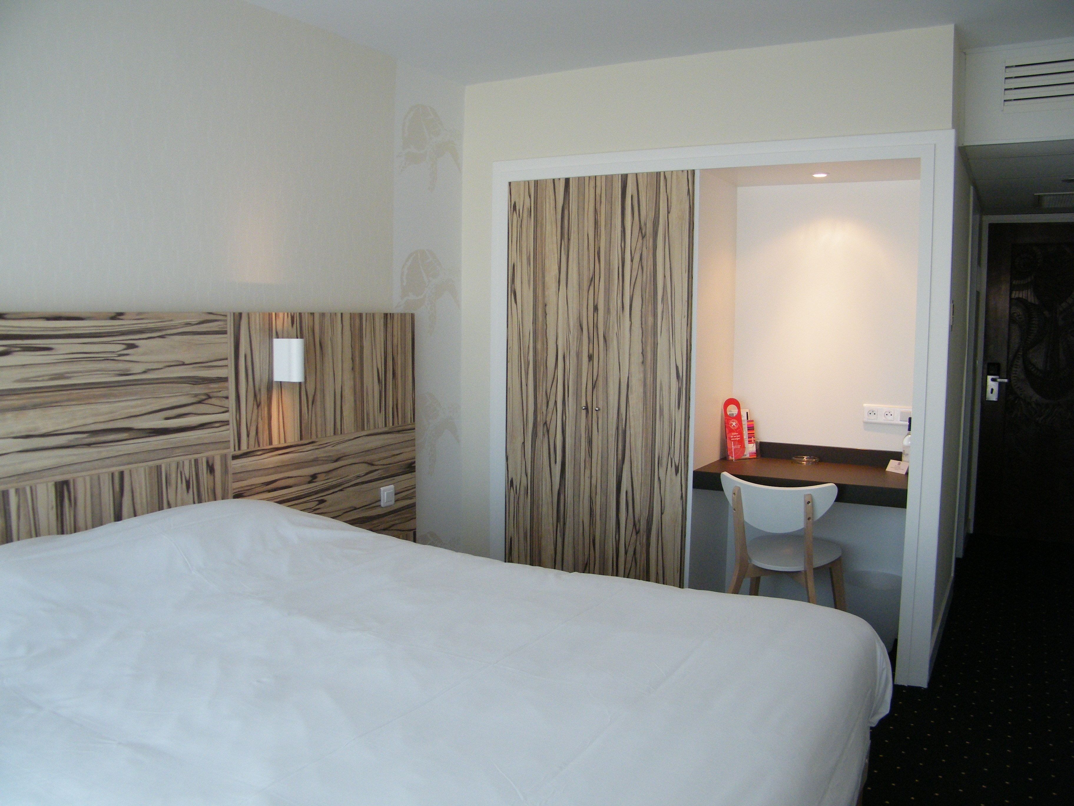 Una habitación de hotel con una cama, un escritorio y una silla.