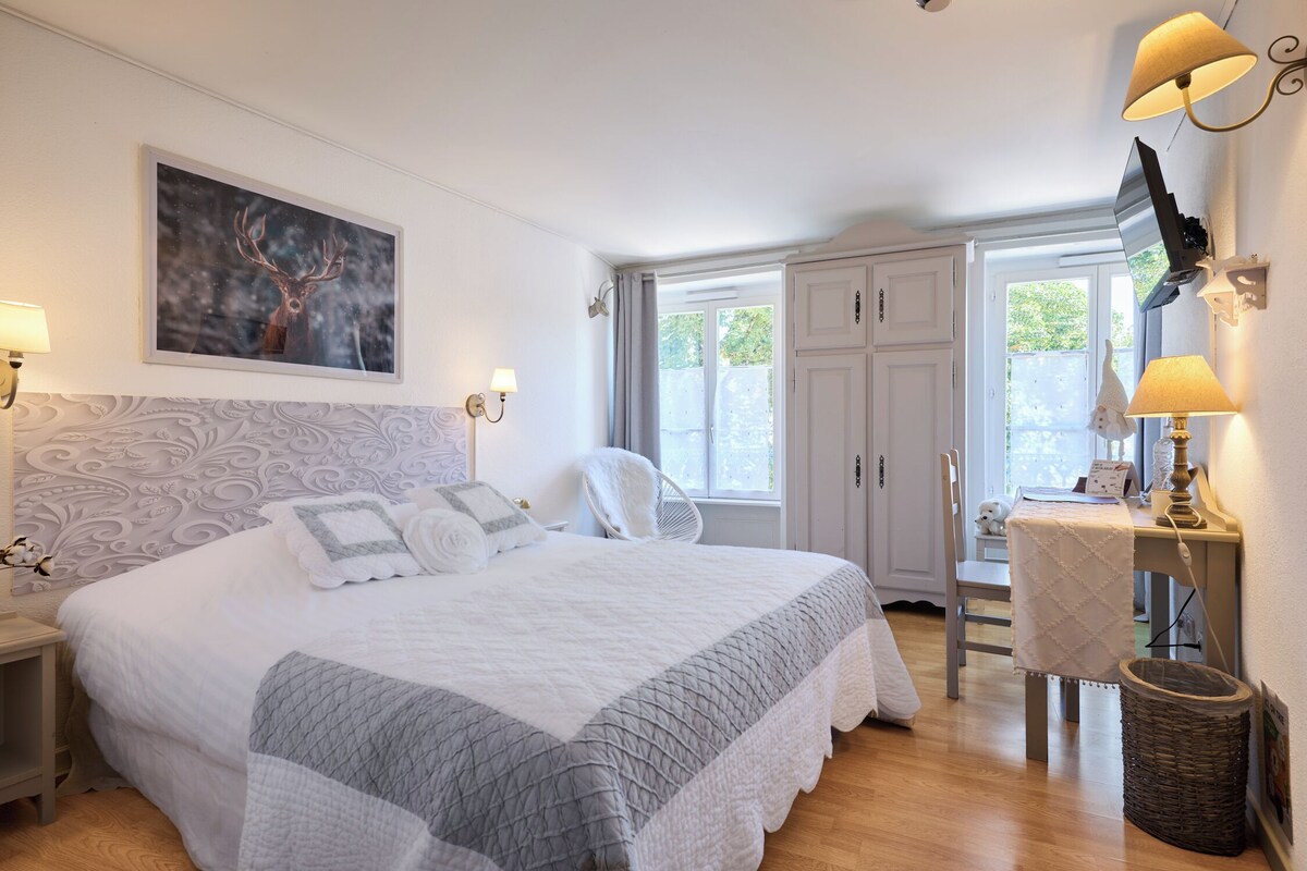 Een slaapkamer met een groot bed, een bureau, een stoel en een televisie.