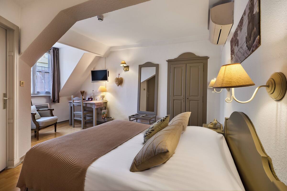 Een hotelkamer met een bed, een bureau, een stoel, een televisie en een kledingkast.