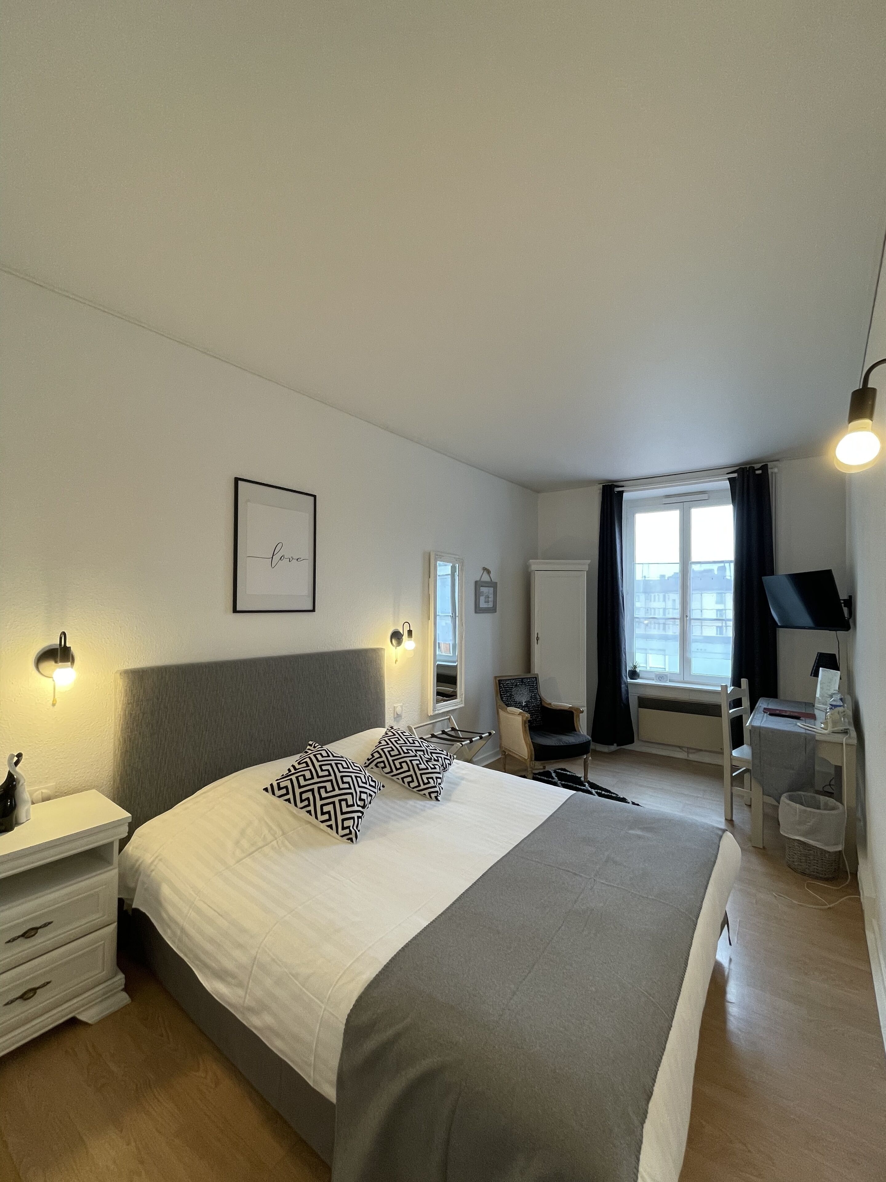Ein modernes Schlafzimmer mit einem großen Bett, Nachttischen, einem Schreibtisch und einem Sessel.