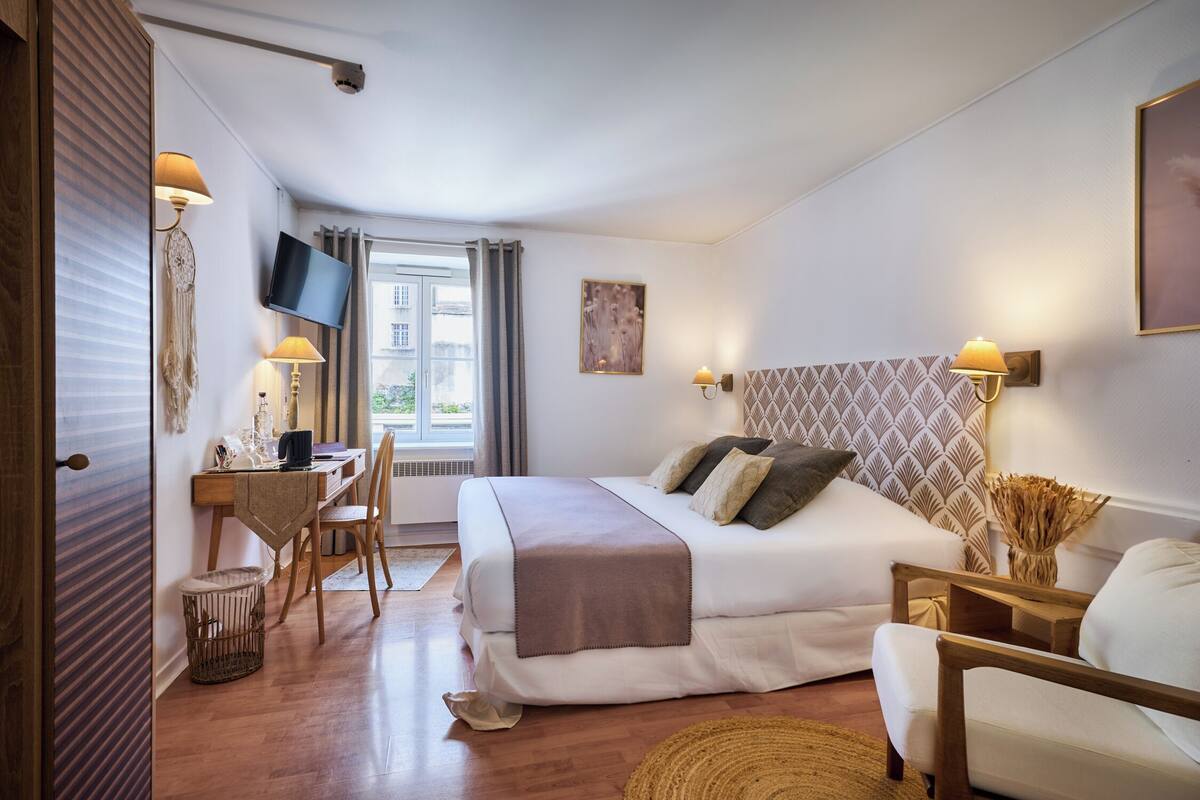 Een slaapkamer met een bed, bureau, stoel en een televisie aan de muur.
