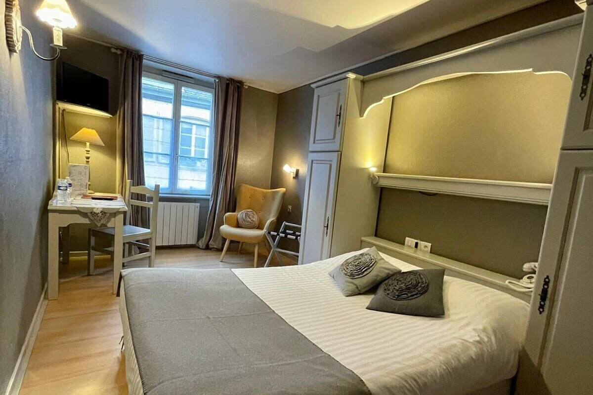 Een hotelkamer met een bed, een bureau, een stoel en een televisie.