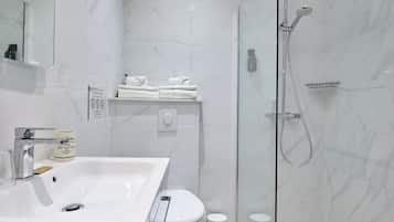A modern bathroom with a glass-enclosed shower, a white sink, and a toilet.