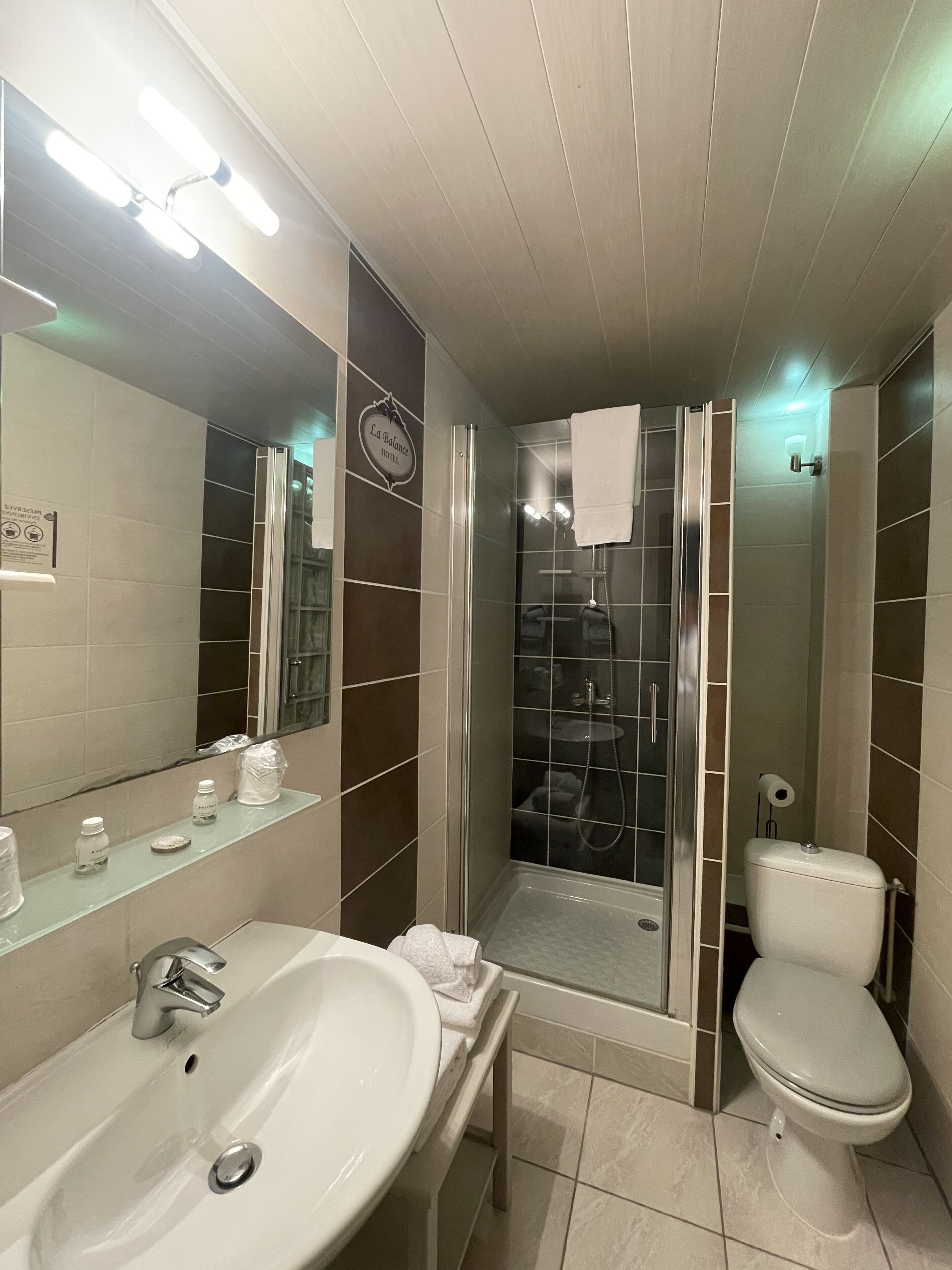 Ein modernes Badezimmer mit großem Spiegel, Waschbecken, Toilette und einer Duschkabine.
