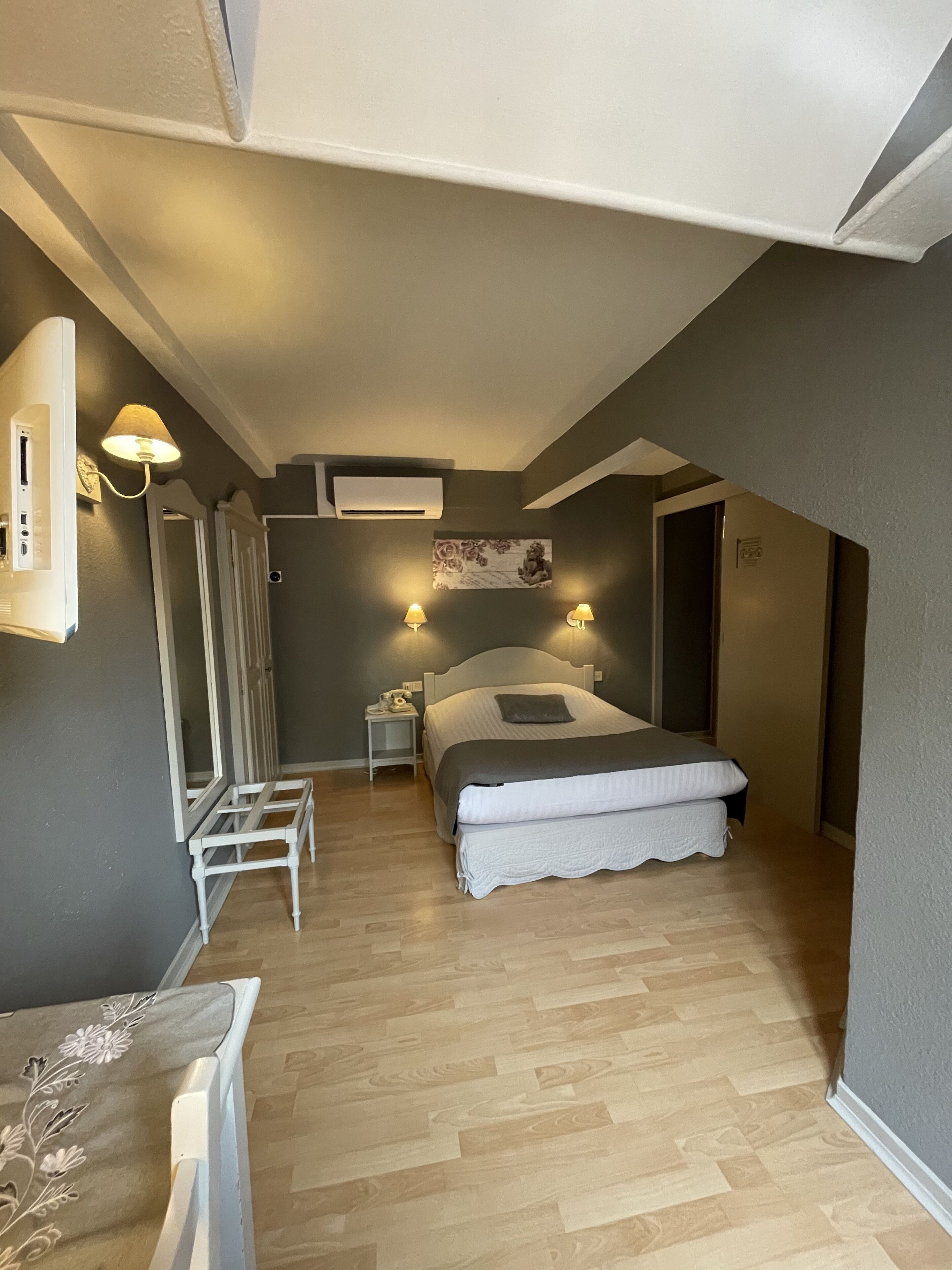 Ein gemütliches Schlafzimmer mit Bett, Nachttischen, einem Spiegel und einer Klimaanlage.