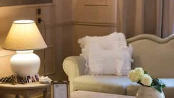 A hotel room with a bed, a bedside table with a lamp, a framed picture, and a vase with flowers.