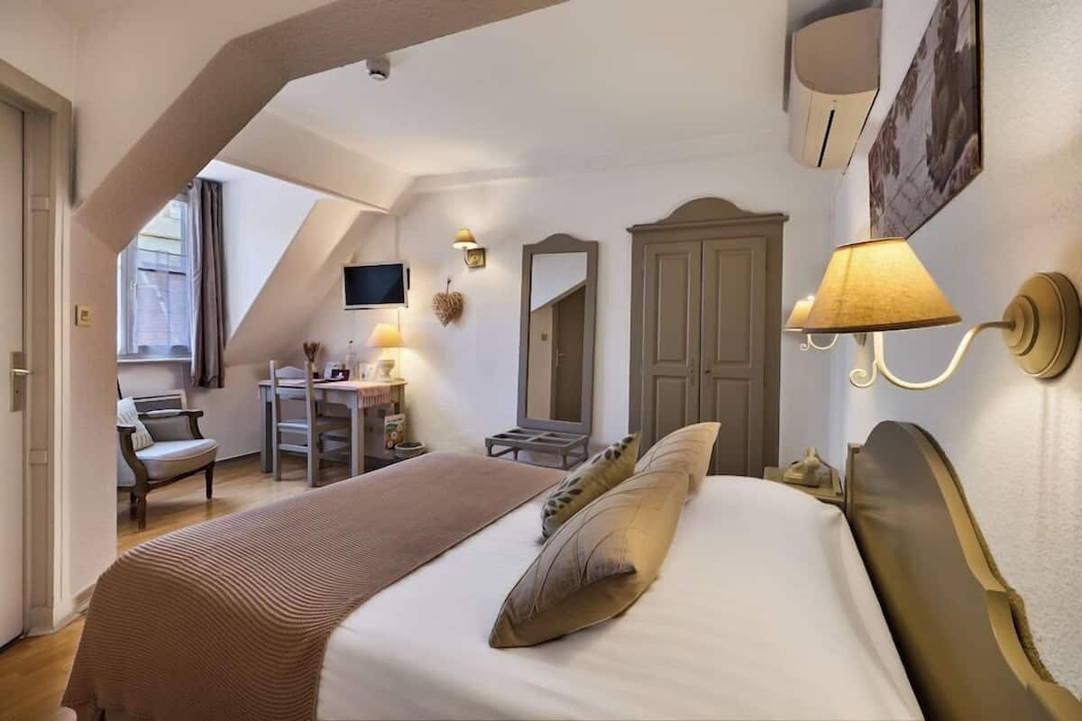 Une chambre à coucher comprenant un lit, un bureau, une chaise, une télévision et une armoire.