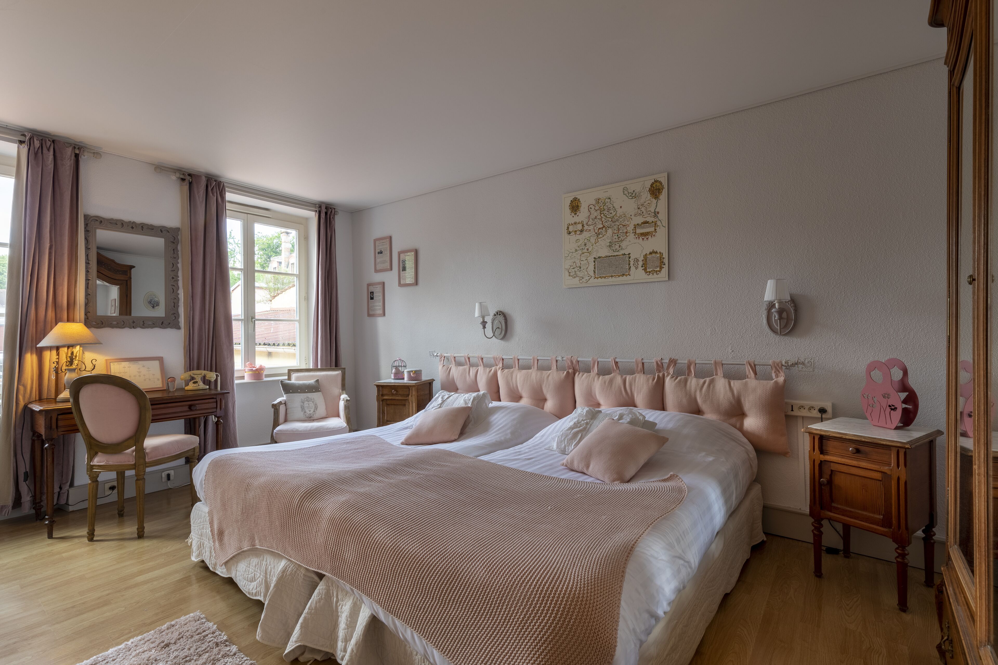 A bedroom with a large bed, a desk, a chair, a dresser, and a mirror.