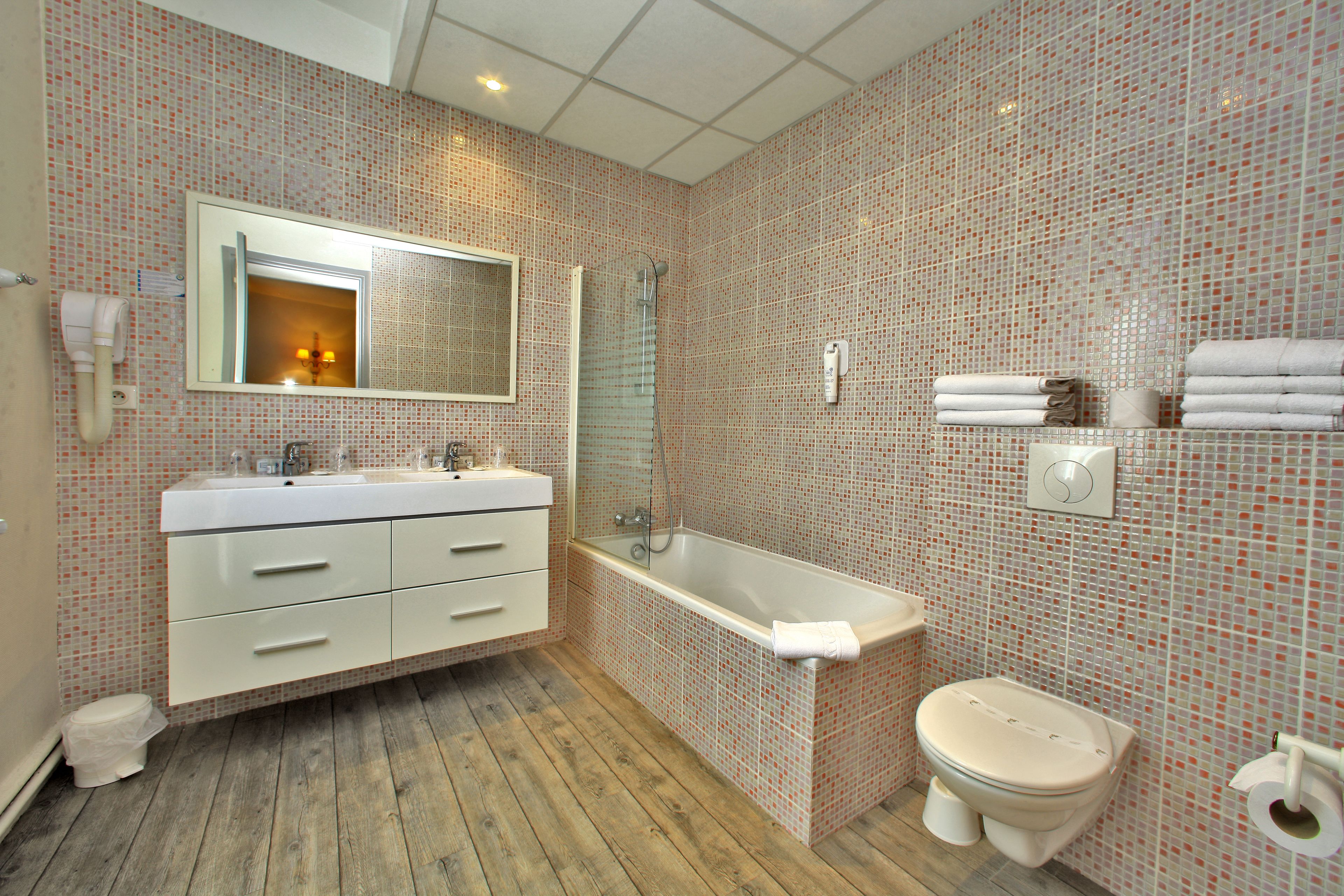 Un bagno con pavimento in legno, lavandino bianco, vasca e water.