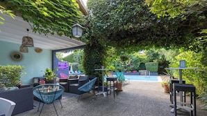 An outdoor patio area with a pool, seating, and greenery.