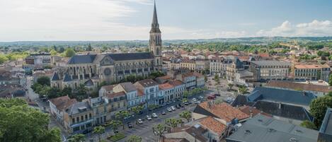 Un pueblo histórico con una iglesia destacada que cuenta con una aguja alta, rodeado de edificios tradicionales y una calle principal con coches estacionados.