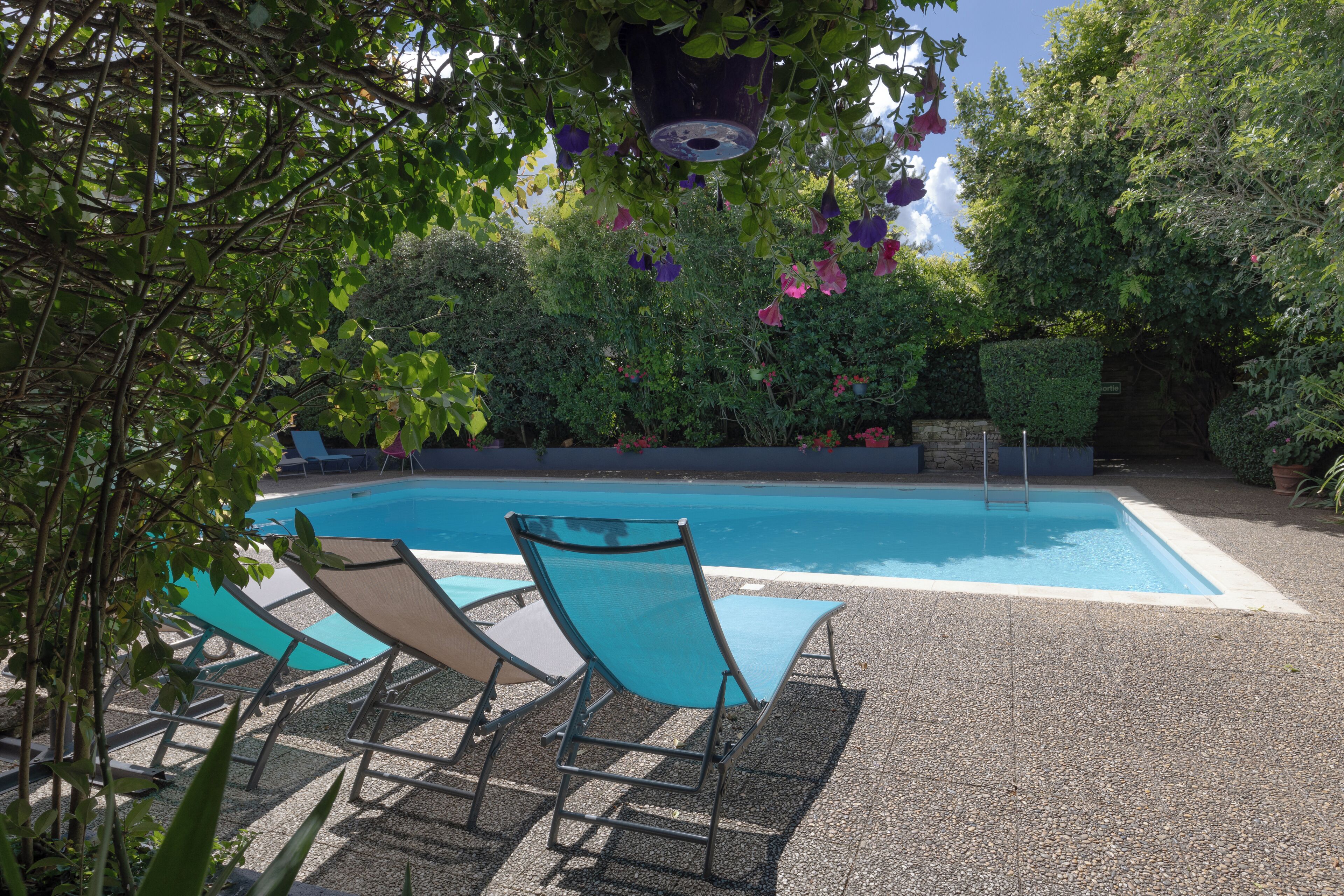 Una piscina con sillones de descanso y una pared de piedra.