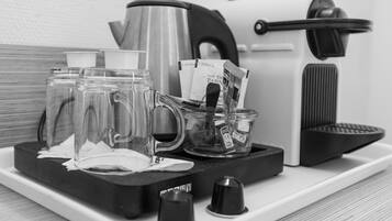 Una cafetera, un hervidor y una bandeja con tazas de café y sobres sobre la encimera.