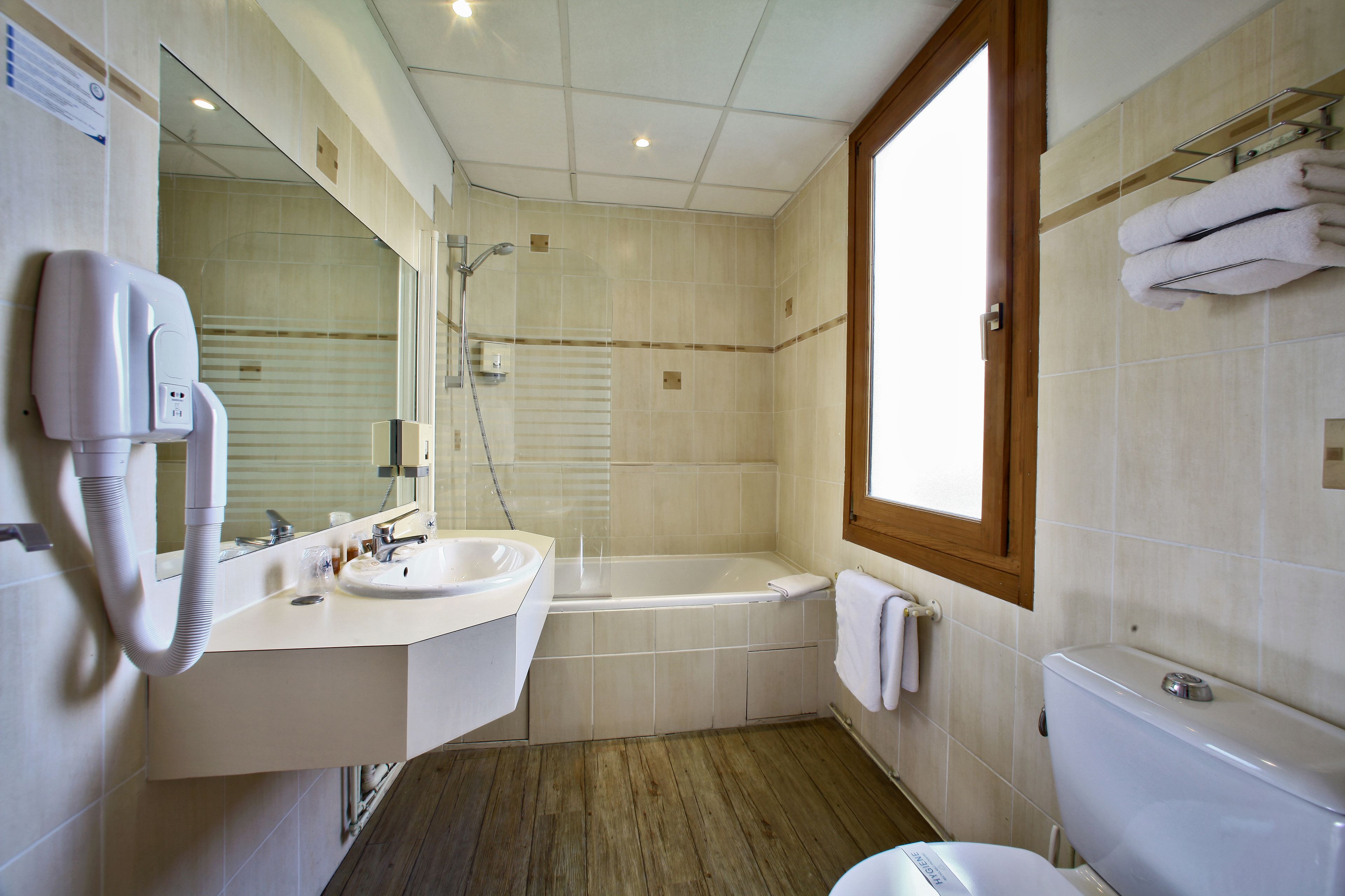 A modern bathroom with a sink, mirror, and a large bathtub.