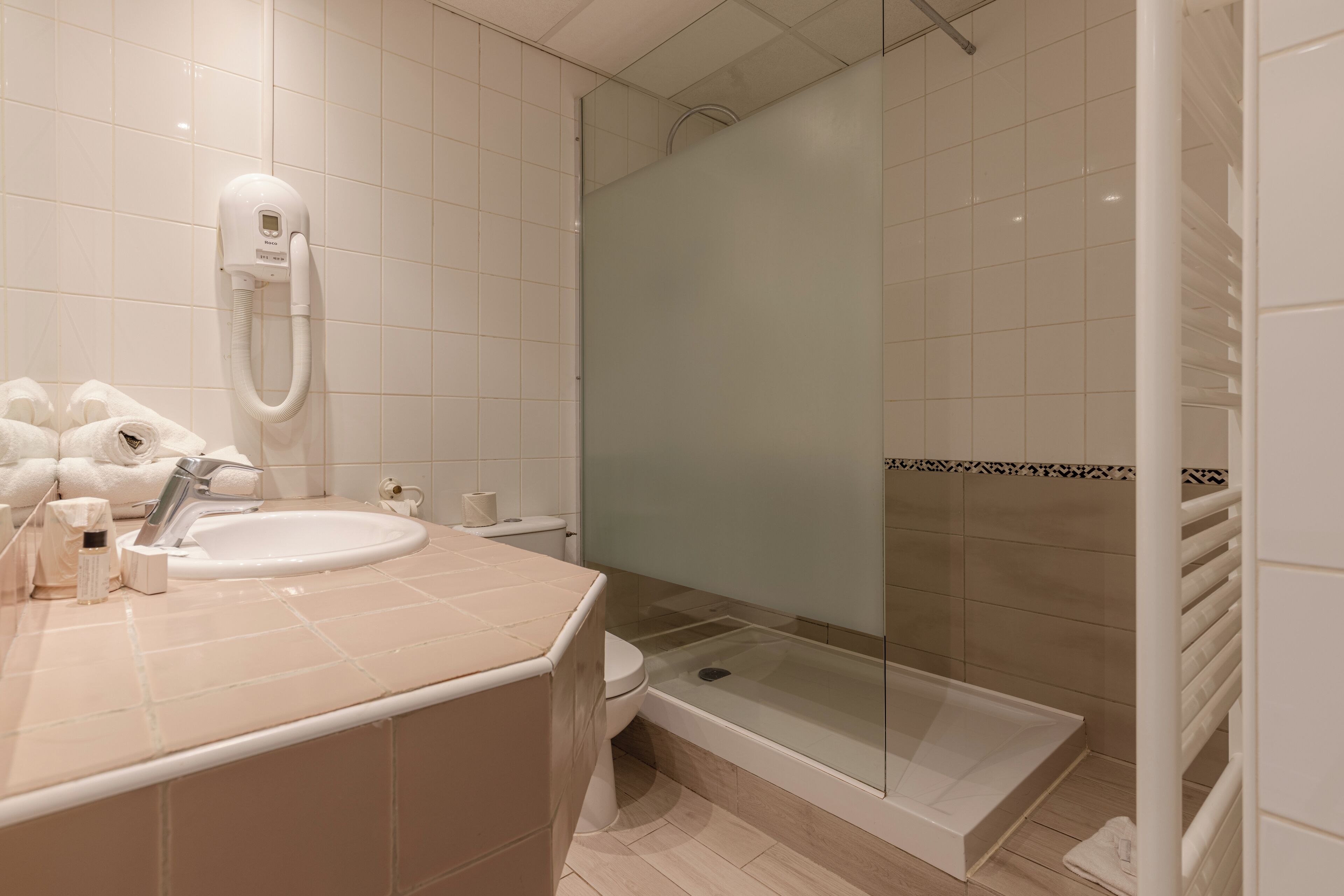 Un baño moderno con lavamanos, inodoro y ducha con mampara de vidrio.