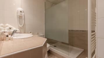 Un baño moderno con lavamanos, inodoro y ducha con mampara de vidrio.