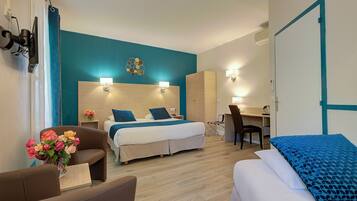 Una habitación de hotel con cama, escritorio, silla, sofá y un jarrón de flores.